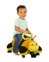 Child riding a yellow bee-shaped toy on a grassy area with a colorful background